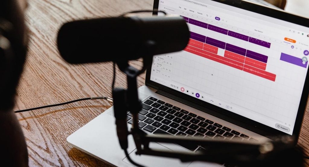 homem gravando podcast no computador com microfone profissional.