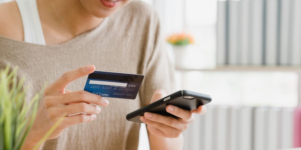 mulher fazendo compra no celular com cartão de crédito.