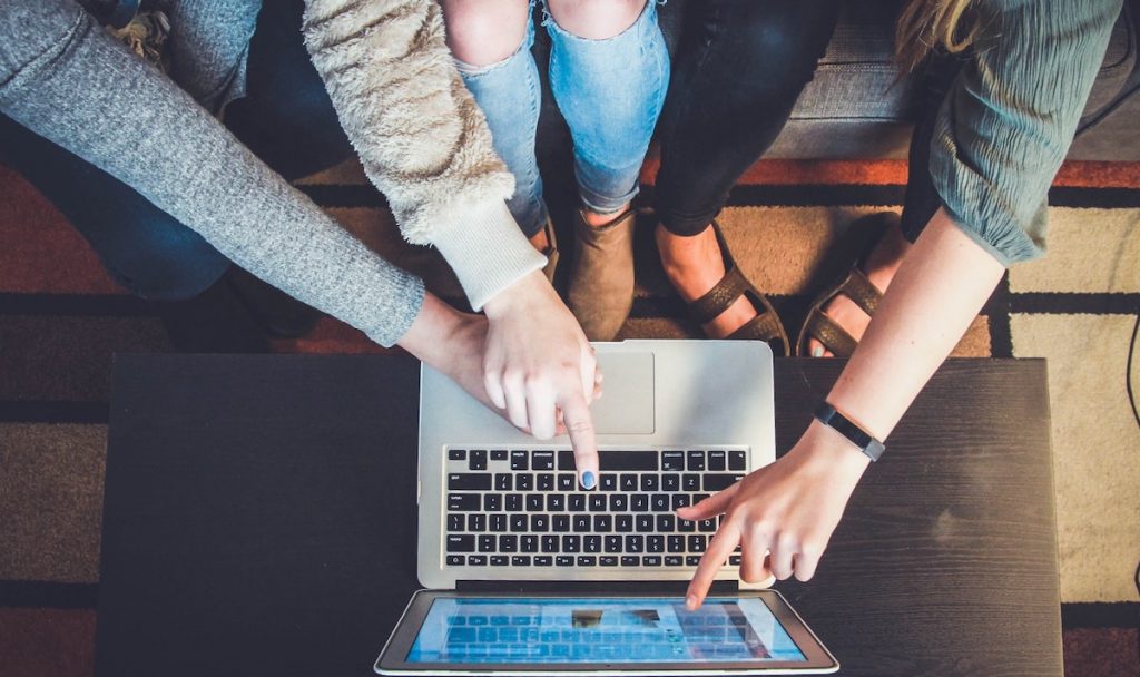 três mulheres apontando para tela do computador