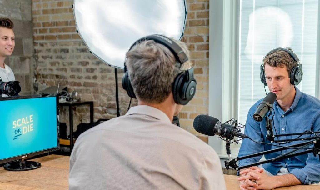 três homens em studio gravando podcast