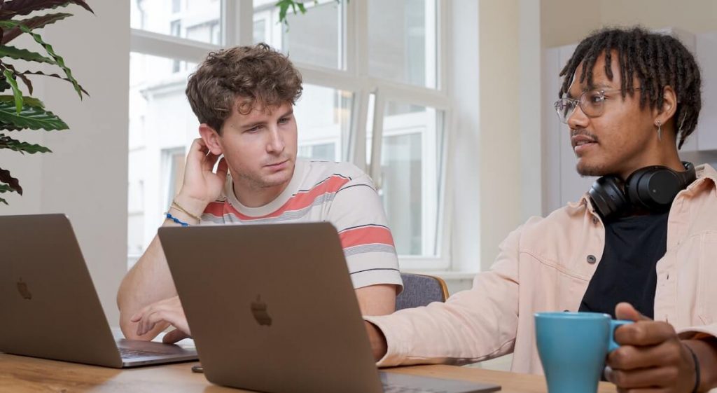 duas pessoas conversam em frente ao notebook