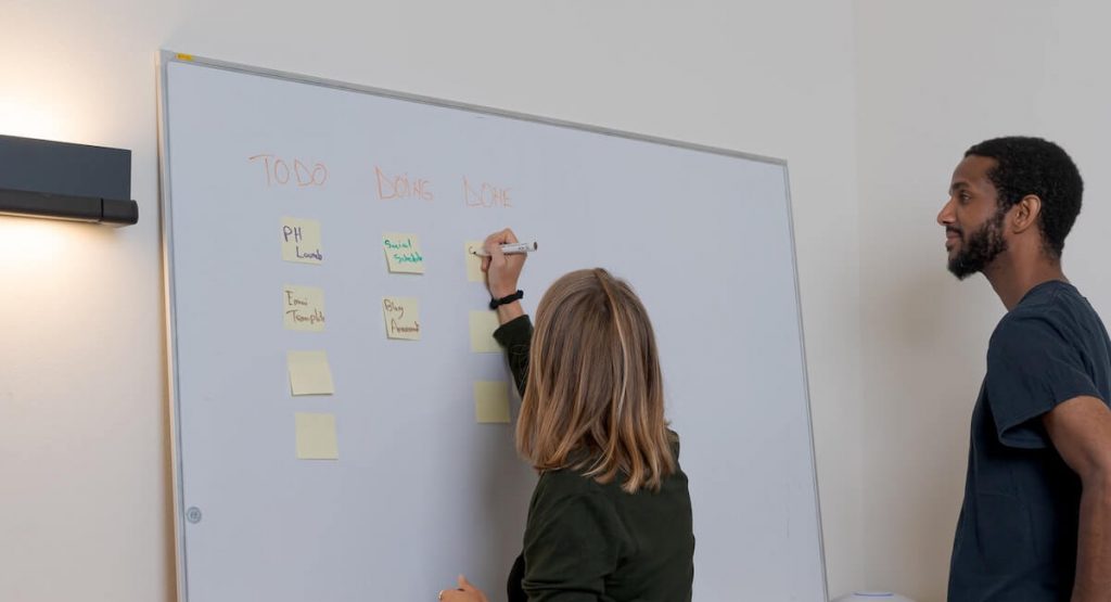 duas pessoas fazem brainstorming em frente ao quadro